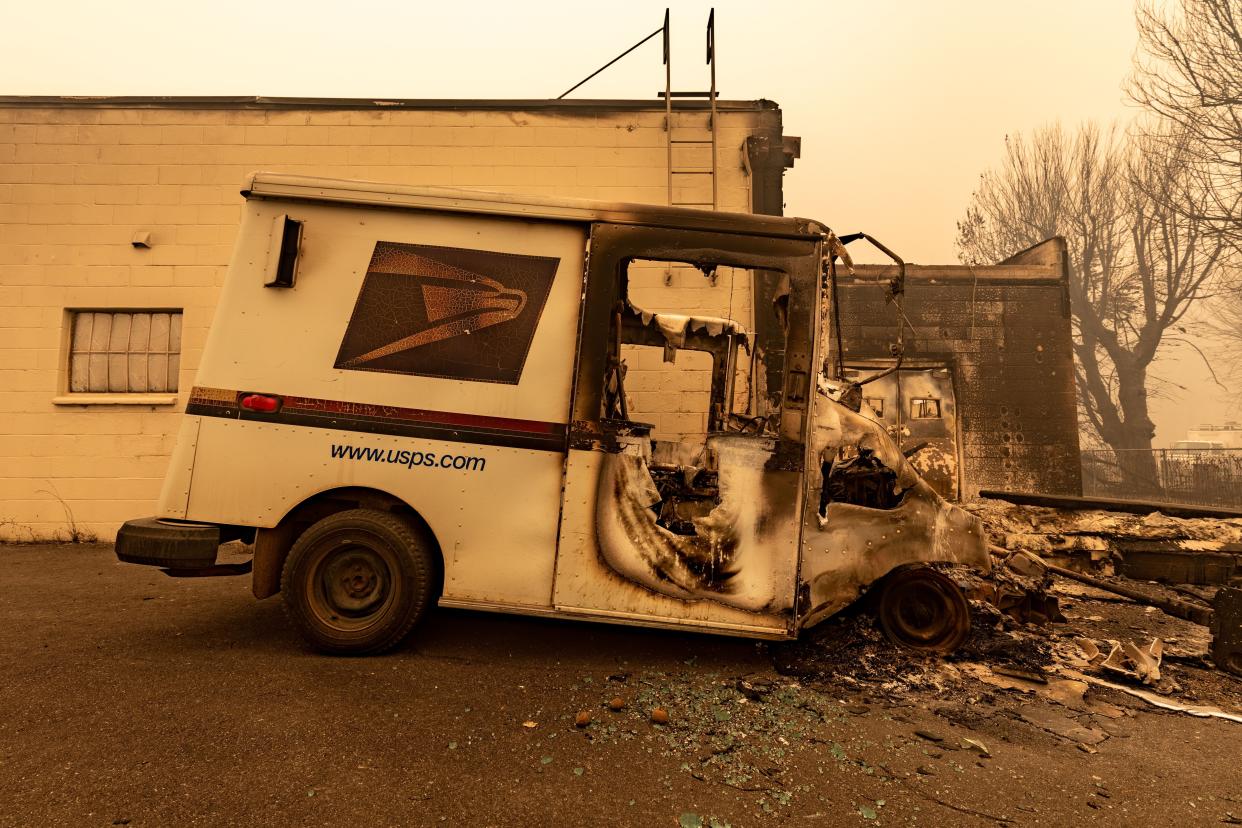 A burned USPS delivery vehicle sits behind the local post office on Aug. 6, 2021, in Greenville, Calif.