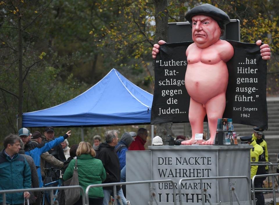 An effigy of German Church reformer Martin Luther reading 'The naked truth about Martin Luther' (on the socle) and 'Hitler precisely executed Luther's advices against the Jews' (in the coat) is seen close to the Schlosskirche (All Saints' Church, Castle Church) in Wittenberg, eastern Germany, where celebrations were under way on the occasion of the 500th anniversary of the Reformation on October 31, 2017.&nbsp; (Photo: HENDRIK SCHMIDT via Getty Images)