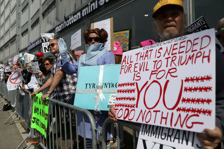 Protesters hold signs near the Intrepid Sea, Air & Space Museum ahead of an expected visit by U.S. President Donald Trump in the Manhattan borough of New York City, U.S., May 4, 2017. REUTERS/Shannon Stapleton