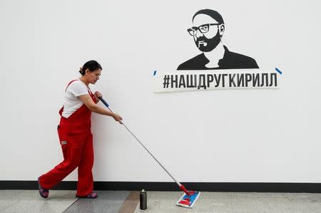 A cleaner mops the floor past the exhibit dedicated to Russian theatre director Kirill Serebrennikov, who was accused of embezzling state funds and placed under house arrest, during a press preview of the Cosmoscow modern art fair in Moscow, Russia September 7, 2017. The inscription reads, "Our friend Kirill". REUTERS/Maxim Shemetov