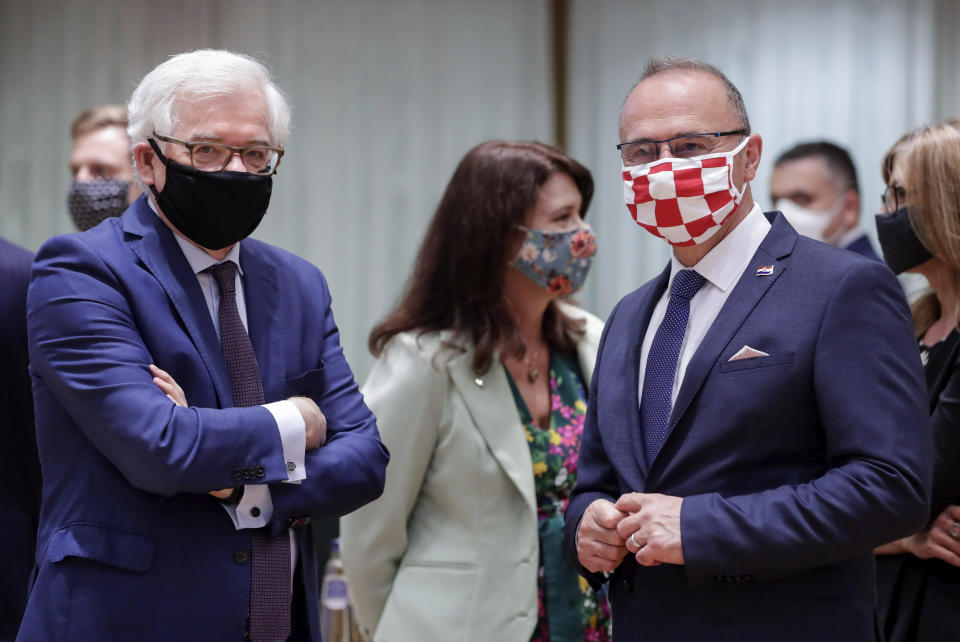 Poland's Foreign Minister Jacek Czaputowicz, left, and Croatia's Foreign Minister Gordan Grlic Radman, right, wear protective face mask, to prevent against the spread of coronavirus, as they attend a meeting of EU foreign ministers at the European Council building in Brussels, Monday, July 13, 2020. European Union foreign ministers meet for the first time face-to-face since the pandemic lockdown and will assess their discuss their relations with China and Turkey. (Stephanie Lecocq, Pool Photo via AP)