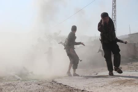 A rebel fighter from the Ahrar al-Sham Islamic Movement covers his ear as he moves with fellow fighters during what they said were clashes with forces loyal to Syria's President Bashar al-Assad, in al-Kafir area at the southern entrance of the town of Jisr al-Shughour, in the province of Idlib in Idlib province May 12, 2015. REUTERS/Stringer