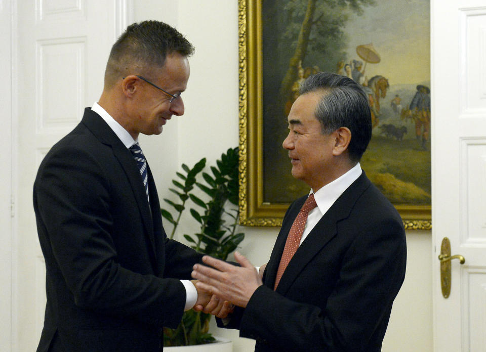 Chinese Foreign Minister Wang Yi, right, shakes hands with Hungarian Minister of Foreign Affairs and Trade Peter Szijjarto during their meeting in the latter's office in Budapest, Hungary, Friday, July 12, 2019. (Lajos Soos/MTI via AP)