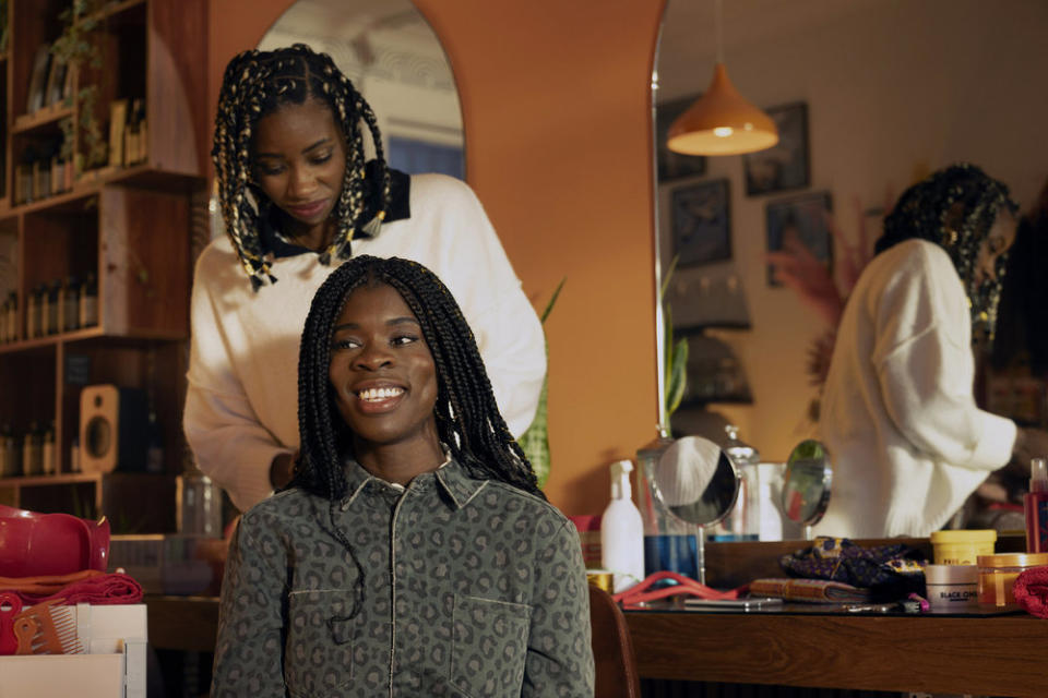 A woman sitting in a salon chair after getting her braids done; Faith Omole in 'We Are Lady Parts'