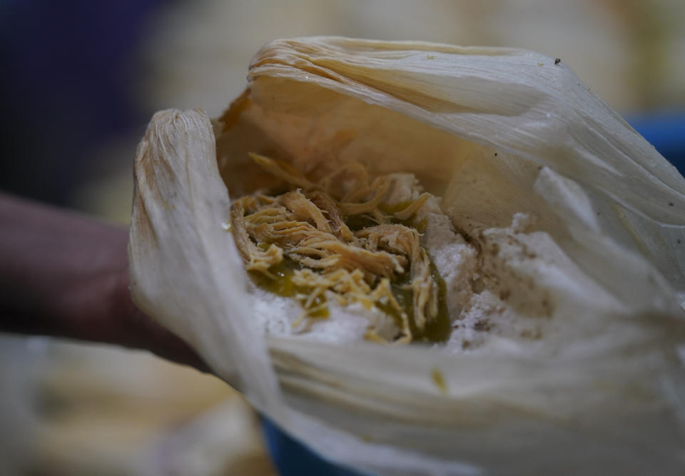 Una mujer rellena tamales con pollo y salsa verde en una vivienda donde se elaboran a mano, en el vecindario de San Felipe de Jesús, en la Ciudad de México, el 25 de enero de 2023. El platillo se remonta a la época prehispánica cuando los olmecas, mexicas y mayas lo utilizaban en rituales religiosos, ofrendas y tumbas. (AP Foto/Fernando Llano)