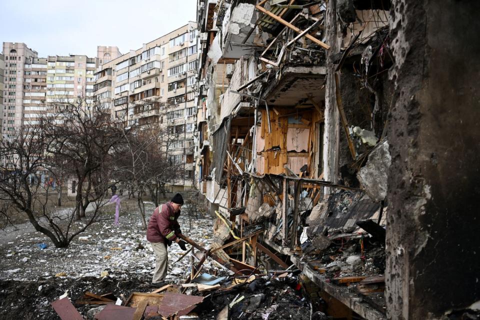 A man clears debris at a damaged residential building in Kyiv.