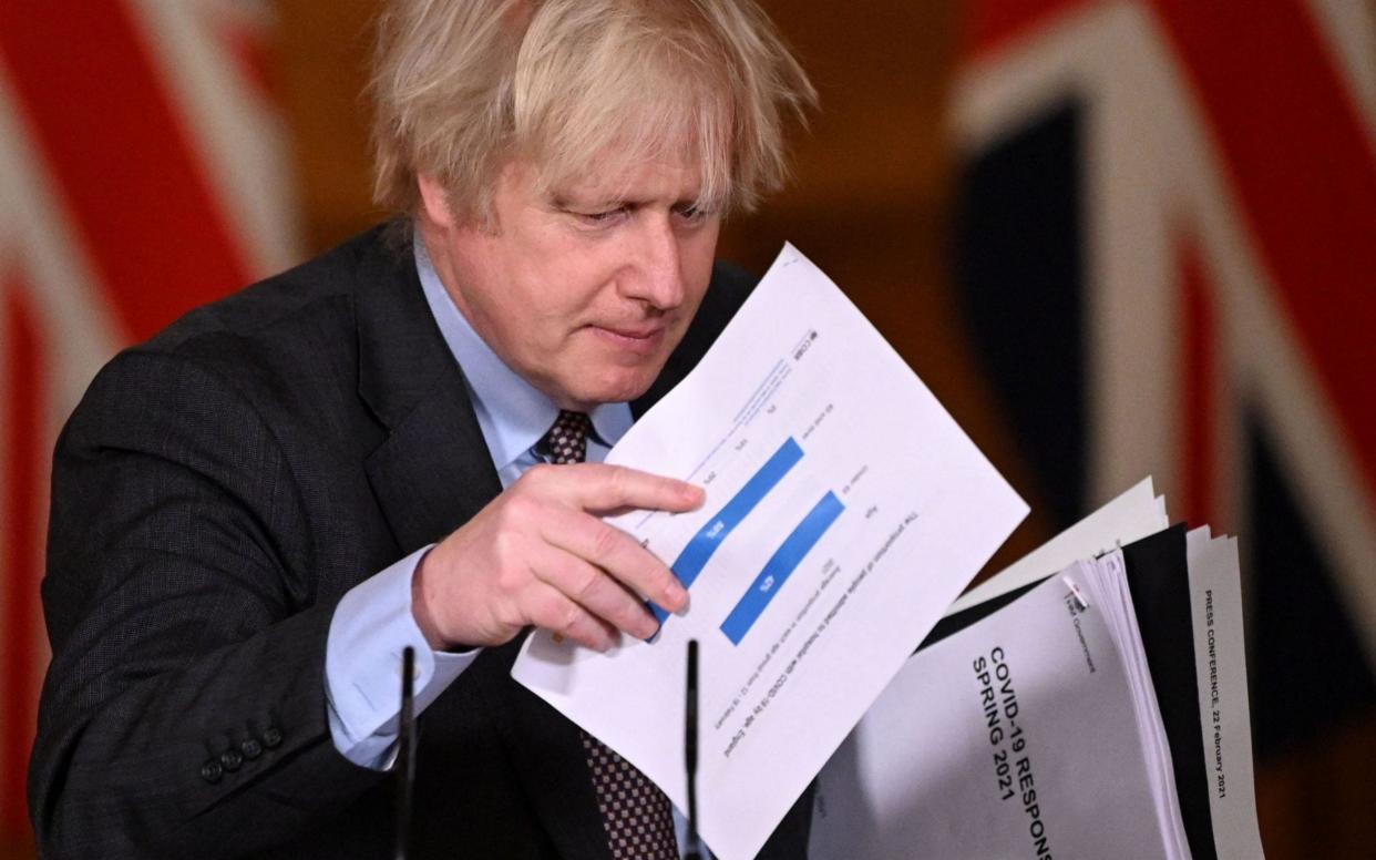 Britain's Prime Minister Boris Johnson gathers his papers as he leaves after a virtual press conference where he set out the Government's roadmap out of the third Covid-19 lockdown. - LEON NEAL/AFP