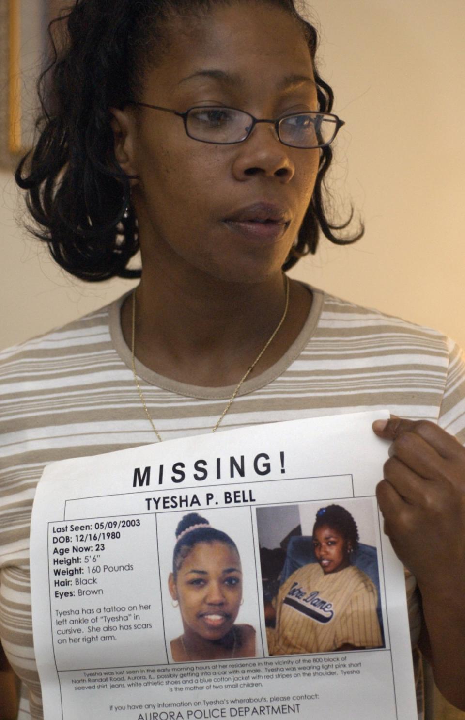 FILE - In this May 6, 2004 photo, Lorna Smith holds a poster of her daughter Tyesha Bell, who has been missing in Glendale Heights, Ill. Authorities say human remains found last year in a wooded area of Chicago’s western suburbs have been identified as Bell, an Aurora mother reported missing in 2003. Aurora Police said Tuesday, March 16, 2021, that Illinois State Police’s crime lab identified Tyesha Bell’s remains through DNA analysis. (Terry Harris/Chicago Tribune via AP)