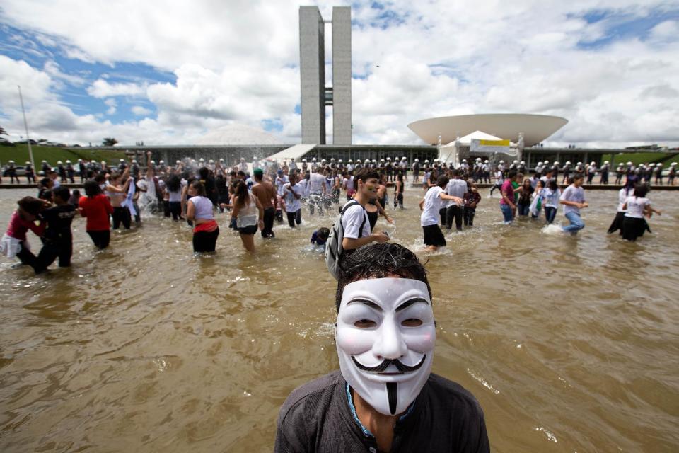 A student wearing a Guy Fawkes mask takes part in a protest in front of the National Congress, in Brasilia, Brazil, Wednesday, March 26, 2014. The protest was organized by the National Union of Students to press deputies to approve the National Education Plan and allocate of 10% of the gross domestic product for education. (AP Photo/Eraldo Peres)