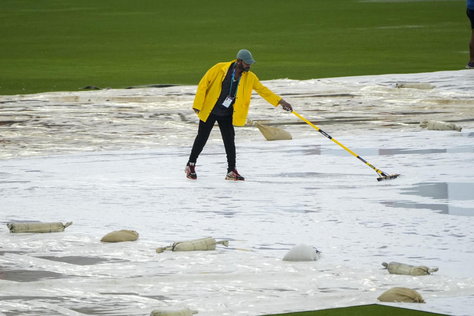 A groundsman sweeps water from the covers as rain delays the start of the men's T20 World Cup cricket match between Sri Lanka and Nepal at Central Broward Regional Park Stadium, Lauderhill, Florida, Tuesday, June 11, 2024. (AP Photo/Lynne Sladky)