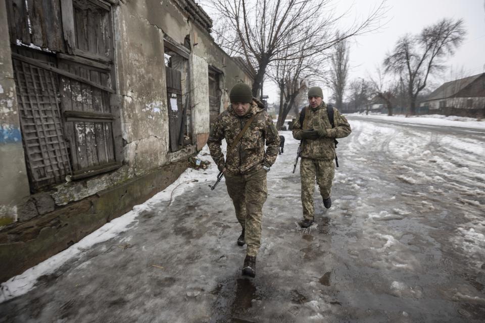 Ukrainian servicemen walk on a road at the line of separation in the Luhansk region, in Luhansk, Ukraine, Thursday, Feb. 3, 2022. When the U.S. and NATO rejected the Kremlin's security demands over Ukraine last week, fears of an imminent Russian attack against its neighbor soared. (AP Photo/Andriy Dubchak)