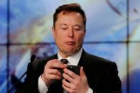 FILE PHOTO: SpaceX founder and chief engineer Elon Musk looks at his mobile phone during a post-launch news conference to discuss the SpaceX Crew Dragon astronaut capsule in-flight abort test at the Kennedy Space Center