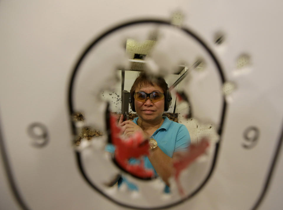 In this Feb. 9, 2014 photo, Bureau of Internal Revenue Commissioner Kim Henares poses with her score following target practice in a firing range at suburban Mandaluyong city, east of Manila, Philippines. The 53-year-old straight-talking chief has shifted her agency into “law enforcement mode” with an aggressive anti-tax evasion campaign to catch cheats and raise collections. Henares is a lawyer and accountant whose hobbies include weekly trips to the firing range where she shoots off automatic pistols and assault rifles. Shooting has become one of her favorite pastimes since she was appointed in July 2010 by President Benigno Aquino III, a gun aficionado who introduced her to the sport. (AP Photo/Bullit Marquez)