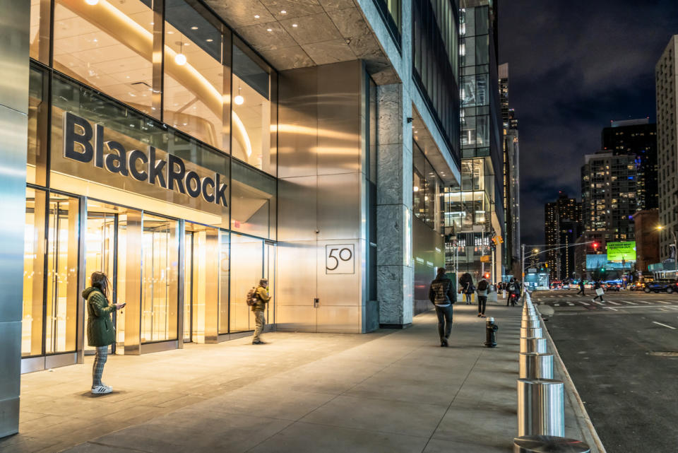 People at night outside the entrance to BlackRock's headquarters office and on the street in Hudson Yards in Manhattan.