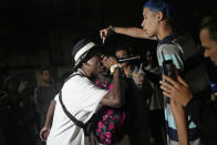 Real Hoppe, left, and Kunk compete at the Gas Battle rapping event outside a bar in the City of God favela of Rio de Janeiro, Brazil, late Wednesday, Nov. 10, 2021. Rap artists in the favela are starting to compete again since the COVID-19 pandemic curtailed public gatherings, presenting local residents with a show in a sign of a return to normalcy for music lovers. (AP Photo/Silvia Izquierdo)