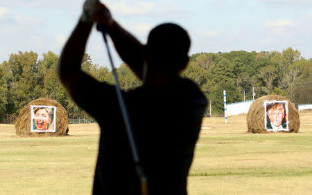 Richard Smith looks at hay bales covered with the portraits of U.S. presidential nominees Hillary Clinton and Donald Trump, which are used as a mock polling station, at Alpine Target Golf Center in Longview, Texas November 2, 2016. REUTERS/Todd Yates