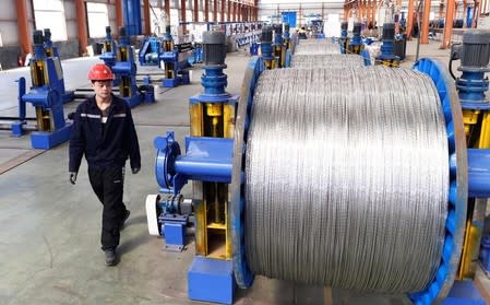 FILE PHOTO: A worker walks past aluminium wires at a plant inside an industrial park in Binzhou