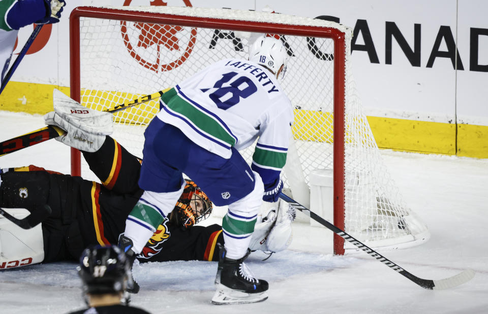 Vancouver Canucks forward Sam Lafferty, right, scores on Calgary Flames goalie Jacob Markstrom during the first period of an NHL hockey game, Saturday, Dec. 2, 2023 in Calgary, Alberta. (Jeff McIntosh/The Canadian Press via AP)