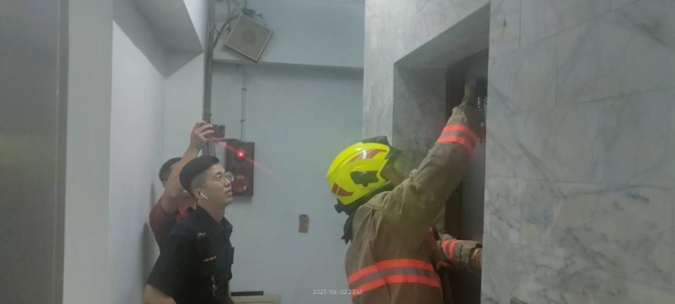 消防隊員以外門鑰匙打開電梯外門，順利讓民眾脫困。（記者張上耕翻攝）
