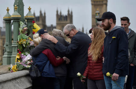 People embrace after laying flowers during an event to mark one week since a man drove his car into pedestrians on Westminster Bridge then stabbed a police officer in London, Britain March 29, 2017. REUTERS/Hannah McKay