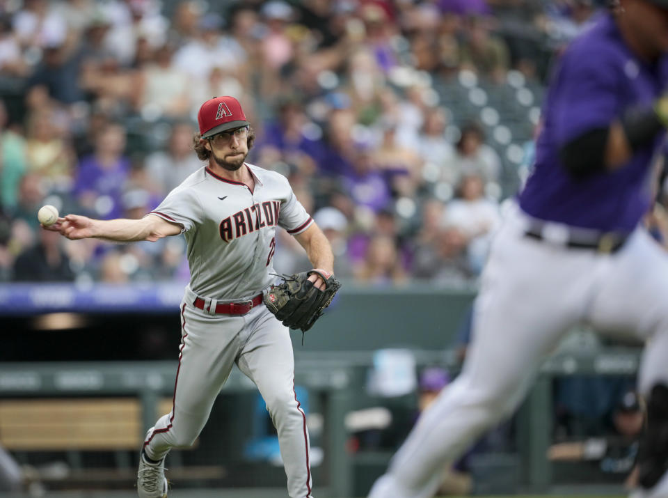 Arizona Diamondbacks starting pitcher Zac Gallen, left, throws out Colorado Rockies baserunner Jose Iglesias in the first inning of a baseball game in Denver, Saturday, Aug. 13, 2022. (AP Photo/Joe Mahoney)