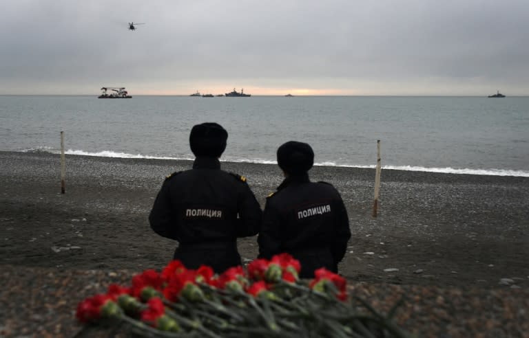 Russian police officers look at the rescue vessels searching the Black Sea outside Sochi two days after the plane crashed on its way to a Russian military airbase in Syria