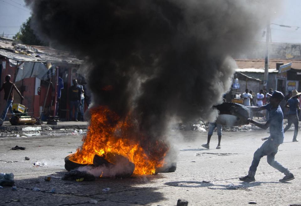 A supporter of presidential candidate Maryse Narcisse burns tires to protest the final election results in Port-au-Prince, Haiti, Tuesday, Jan. 3, 2017. An electoral tribunal certified the presidential election victory of first-time candidate Jovenel Moise. (AP Photo/Dieu Nalio Chery)
