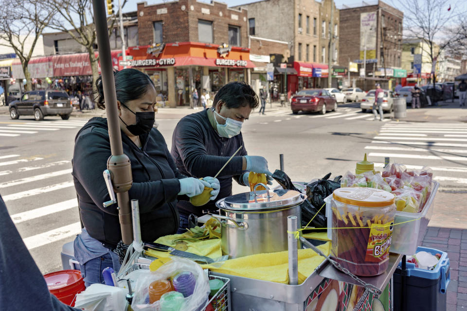 Ruth Palacios and Arturo Xelo, a married couple from Mexico, work at their fruit stand in the Corona neighborhood of the Queens borough of New York on Tuesday, April 13, 2021. They worked seven days a week for months disinfecting COVID-19 patient rooms at the Memorial Sloan Kettering Cancer Center in New York City, but weren't paid overtime Palacios says. The couple filed a federal lawsuit against the contractor that hired them, alleging their pay was cut without their knowledge from $15 an hour to $12.25. They're now selling fruit to make ends meet. (AP Photo/Marshall Ritzel)