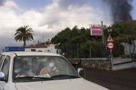 Residents leave their house as lava continues to flow from an erupted volcano, in La Mancha on the island of La Palma in the Canaries, Spain, Friday, Sept. 24, 2021. A volcano in Spain’s Canary Islands continues to produce explosions and spew out lava, five days after it erupted. Two rivers of lava continue to slide slowly down the hillside of La Palma on Friday. (AP Photo/Emilio Morenatti)