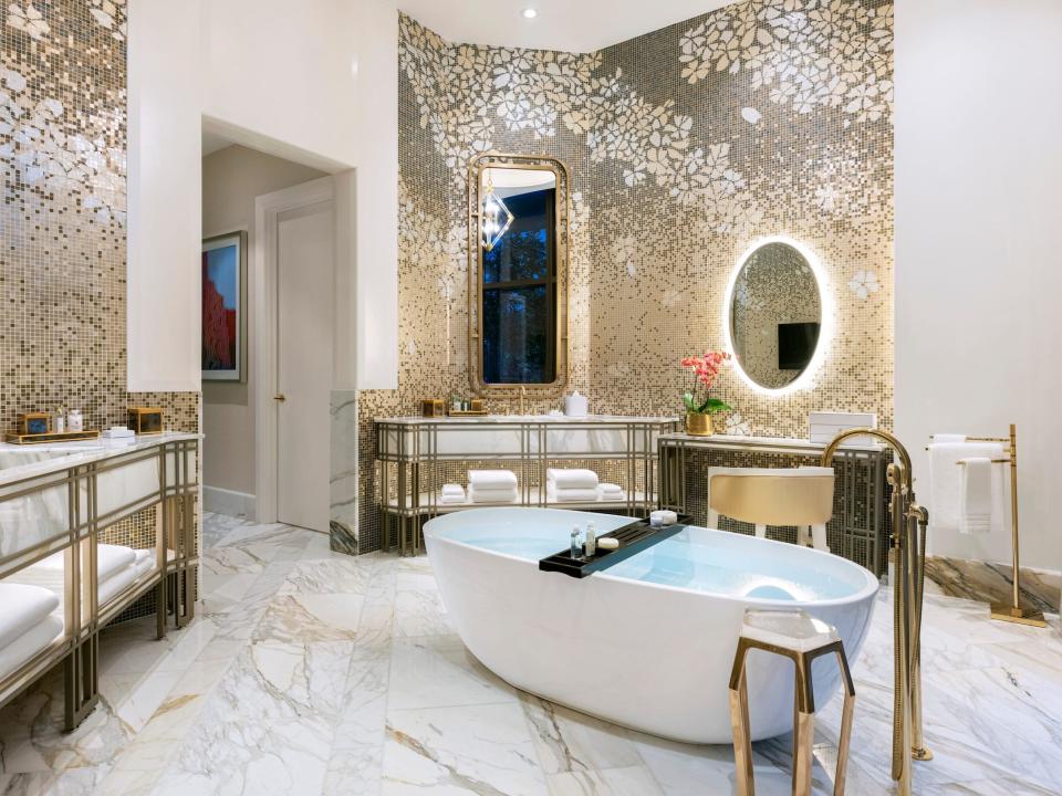 a soaking tub in a bathroom surrounded by gold accents and decor