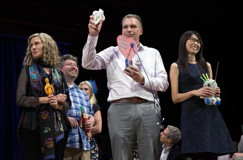 Hanyu Liang, right, and her team receive the Ig Nobel award for economics during ceremonies at Harvard University in Cambridge, Mass., Thursday, Sept. 13, 2018. The team won for investigating whether it is effective for employees to use Voodoo dolls to retaliate against abusive bosses. (AP Photo/Michael Dwyer)