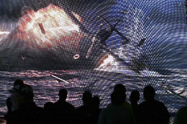 Show attendees watch a presentation on the video game "World of Warships" at the Wargaming.net booth during the Electronic Entertainment Expo in Los Angeles, Wednesday, June 12, 2013. (AP Photo/Jae C. Hong)