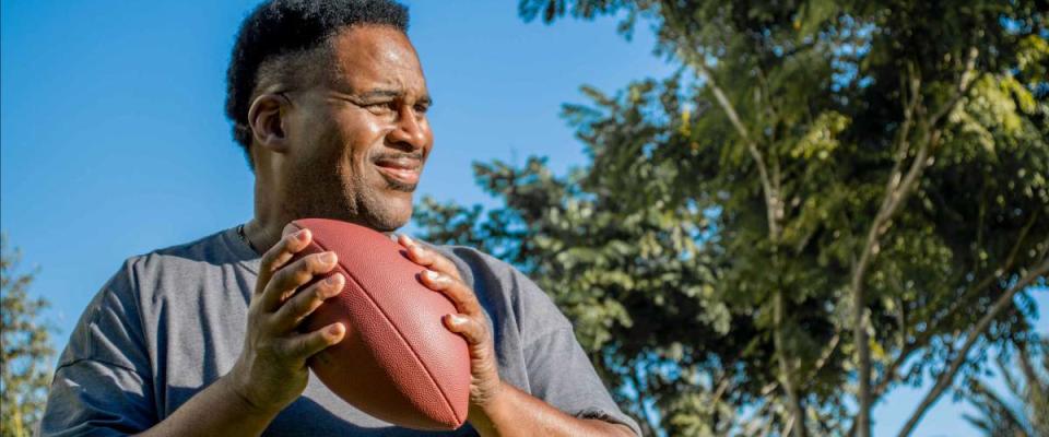 close up of middle aged black man with football outside in sunshine