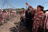 <p>Winnie Madikizela-Mandela, former wife of Nelson Mandela, greets demonstrators behind razor wire at a bail hearing for businessman Piet Odendaal in Viljoenskroon, in the Orange Free State, South Africa, Nov. 10, 2000. Odendaal was accused of murdering a black employee and dragging his body behind a truck in the nearby town of Sasolburg. (Photo: Lori Waselchuk/AP) </p>