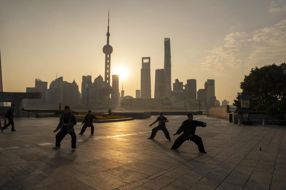 People practice tai chi in front of buildings in Pudong's Lujiazui Financial District in Shanghai, China, on Monday, Feb. 19, 2024.