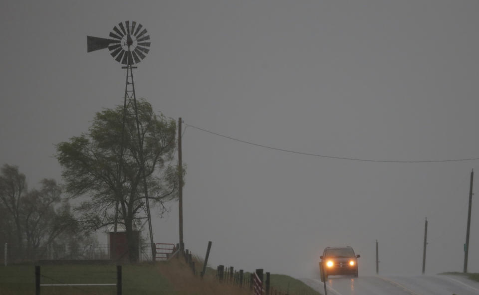 A vehicle tops a hill along U.S. Route 56 as a severe thunderstorm moves through the area near Baldwin City, Kan., Sunday, April 27, 2014. Severe storms are expected in the area most of the day. (AP Photo/Orlin Wagner)