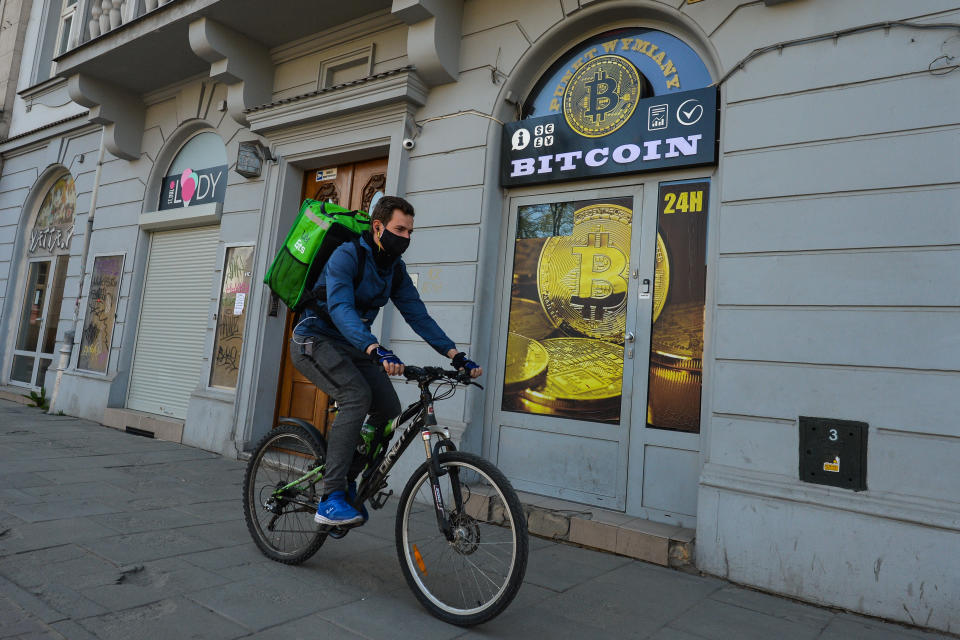 A Uber Eats currier wearing a protective mask passes in front of a Bitcoin exchange shop in Krakow's city center. On Saturday, April 18, 2020, in Krakow, Poland. (Photo by Artur Widak/NurPhoto via Getty Images)