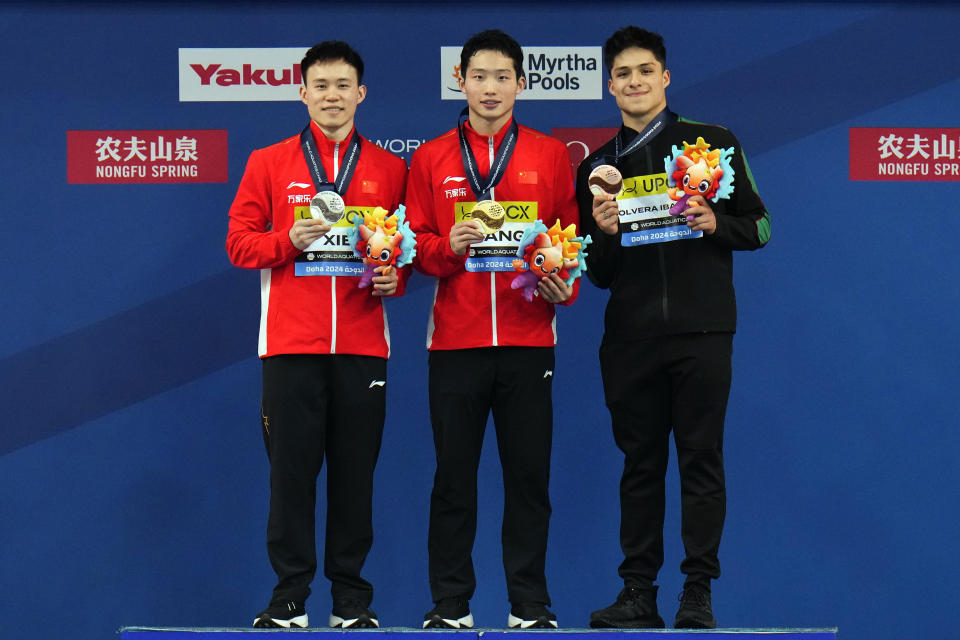 Silver medalist Xie Siyi of China, gold medalist Wang Zongyuan of China and bronze medalist Osmar Olvera Ibarra of Mexico, from left, pose on the podium of the men's 3m springboard diving final at the World Aquatics Championships in Doha, Qatar, Wednesday, Feb. 7, 2024. (AP Photo/Hassan Ammar)