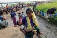 A Rohingya refugee woman who crossed the border from Myanmar a day before, carries her daughter and searches for help as they wait to receive permission from the Bangladeshi army to continue their way to the refugee camps, in Palang Khali, Bangladesh October 17, 2017. REUTERS/Jorge Silva