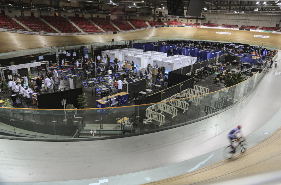 A riders trains at the National Velodrome at Saint-Quentin-en-Yvelines, west of Paris, Saturday, March 27, 2021, that has been transformed into a mass vaccination center. Saturday marked the first day in France of vaccination for healthy people aged 70 and above. (AP Photo/John Leicester)