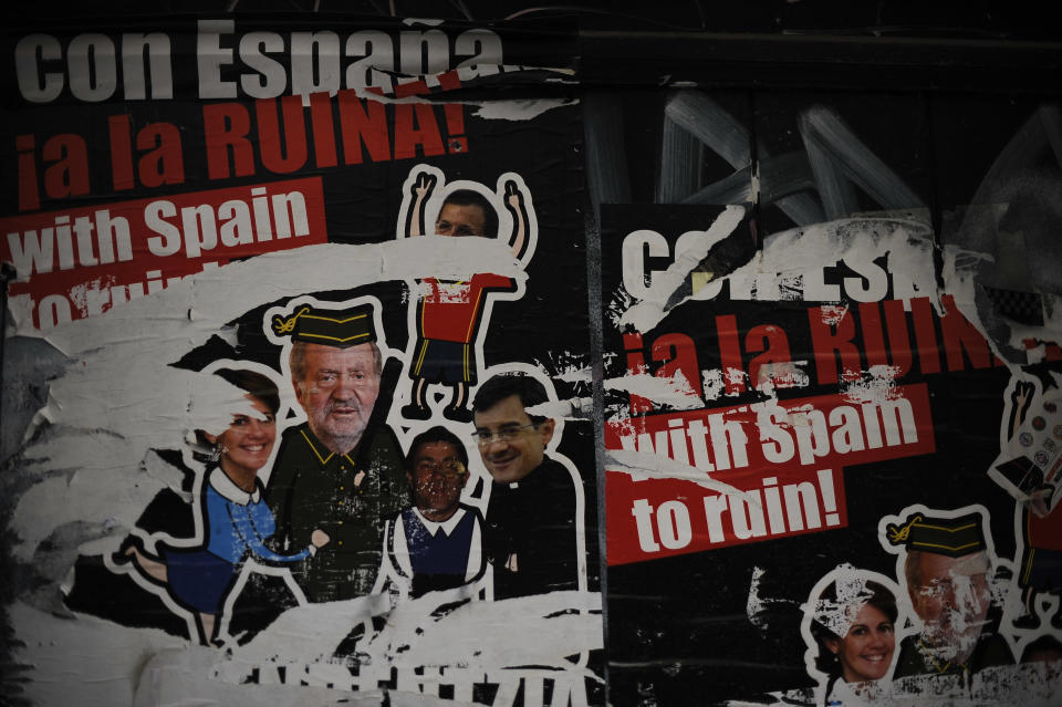 Posters against Spanish King Juan Carlos, left and bottom right, seen on a wall reading, ''With Spain to ruin'', during the celebration of the day of workers, May Day, in Pamplona, northern Spain on Wednesday, May 1, 2013. (AP Photo/Alvaro Barrientos)