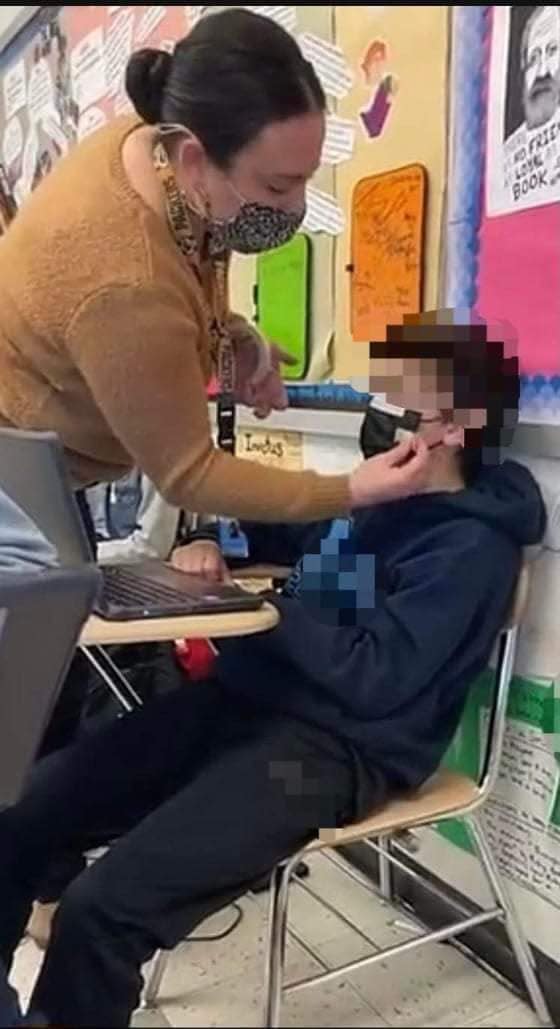 A photo apparently taken at a school in the North Penn School District shows an employee taping a mask onto the blurred-out face of a student.