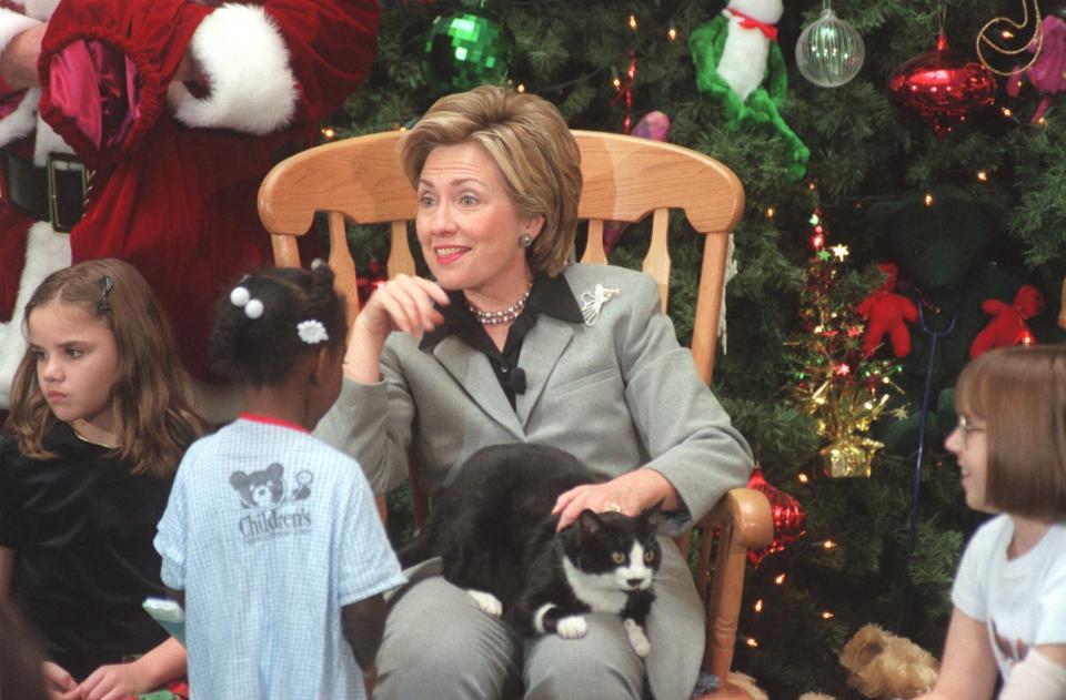 FILE - First lady Hillary Rodham Clinton pets Socks the cat on her lap as she talks with children at the Children's National Medical Center in Washington on Dec. 15, 1999. President Joe Biden and first lady Jill Biden have added a green-eyed tabby from Pennsylvania to the White House family. She's the first feline tenant since President George W. Bush’s controversially named cat India. With Presidents James K. Polk and Donald Trump among notable, no-pets exceptions, animals have a long history in the White House. (AP Photo/George Bridges, File)
