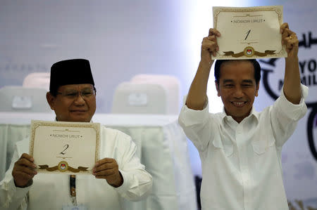 Indonesian President Joko Widodo (R) and his opponent in next year's presidential elections Prabowo Subianto, a retired special forces commander, hold their ballot numbers during a ceremony at the election commission headquarters in Jakarta, Indonesia, September 21, 2018. REUTERS/Darren Whiteside