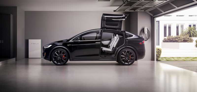 A Model X in a garage with its falcon wing doors open.