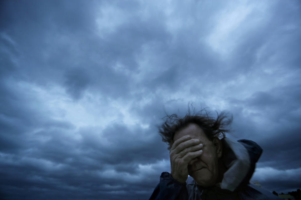 FILE - In this Friday, Sept. 14, 2018 file photo, Russ Lewis covers his eyes from a gust of wind and a blast of sand as Hurricane Florence approaches Myrtle Beach, S.C. According to a scientific report from the United Nations released on Wednesday, March 13, 2019, climate change, a global major extinction of animals and plants, a human population soaring toward 10 billion, degraded land, polluted air, and plastics, pesticides and hormone-changing chemicals in the water are making the planet an increasing unhealthy place for people. (AP Photo/David Goldman)