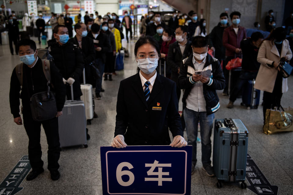 Passengers wear face masks as they stand in line to have temperature checks taken at Wuchang railway station in Wuhan.