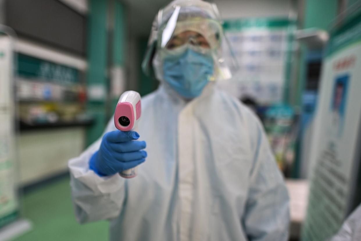 A medical worker prepares to check the temperature of an AFP photojournalist before a COVID-19 coronavirus test in Wuhan in China's central Hubei province