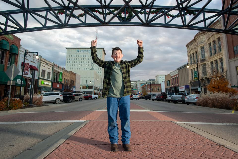 Wyatt Starz, 11, raises his arms Tuesday in the middle of S. Kansas Avenue in downtown Topeka as he prepares for his big role as junior grand marshal of this year's Miracle on Kansas Avenue parade. Starz, a fifth-grader at Wanamaker Elementary School, was selected because of his efforts to help children who are bullied.