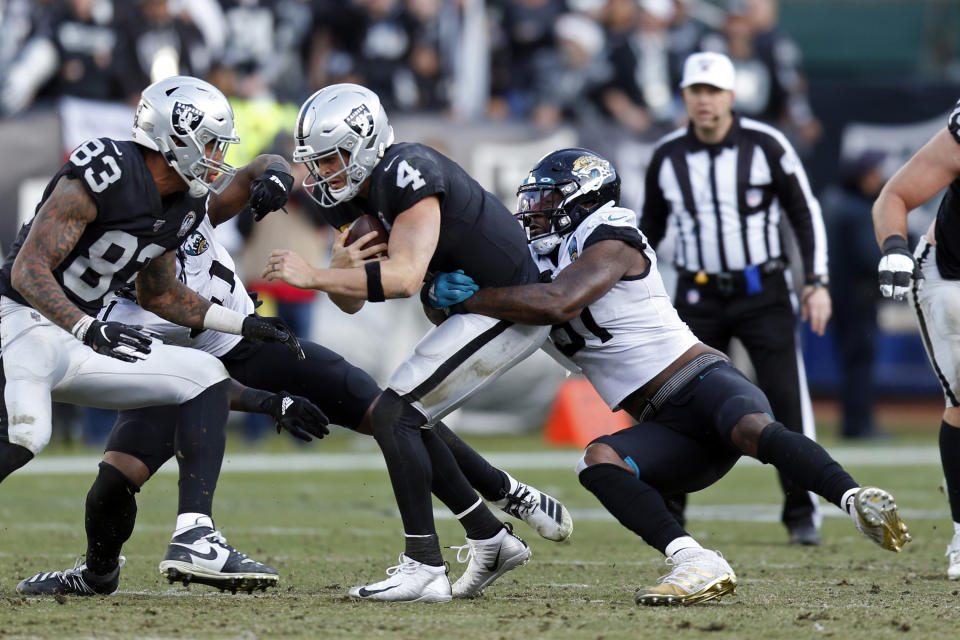 Oakland Raiders quarterback Derek Carr (4) is sacked by Jacksonville Jaguars defensive end Yannick Ngakoue as Raiders tight end Darren Waller (83) looks on during the second half of an NFL football game in Oakland, Calif., Sunday, Dec. 15, 2019. (AP Photo/D. Ross Cameron)